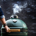 hand opening large biggreenegg with smoke