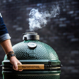 hand opening large biggreenegg with smoke
