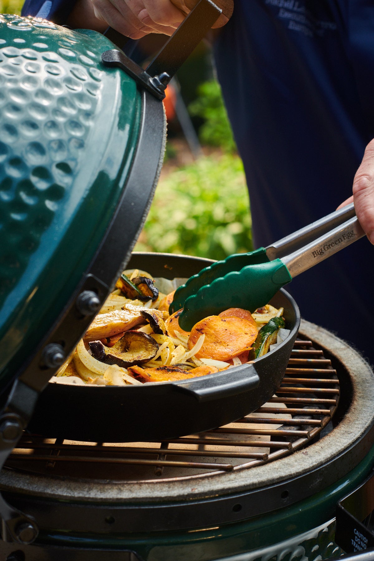 Person cooking a stir fry on a Big Green Egg outdoors