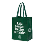 Green tote bag with 'Life tastes better outside' text on a white background