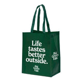Green tote bag with 'Life tastes better outside' text on a white background