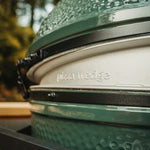 Close-up of a big green egg modified to be a pizza oven with 'pizza wedge' branding outdoors.