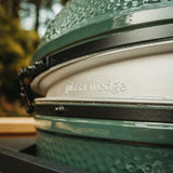 Close-up of a big green egg modified to be a pizza oven with 'pizza wedge' branding outdoors.