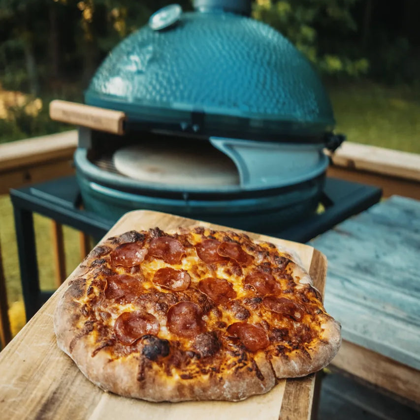 pizza going into a ceramic kamado grill