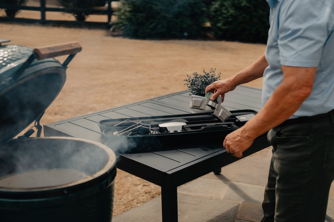 Person using a portable rotisserie accessory on a patio