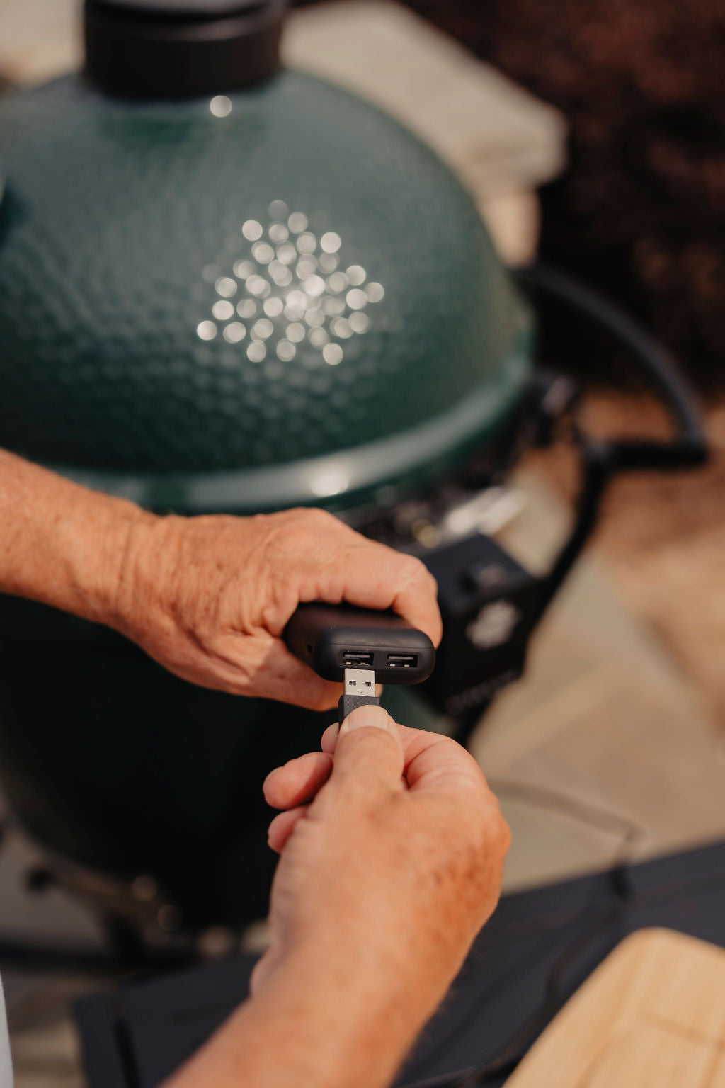 Person plugging a USB cable into a large big green grill accessory