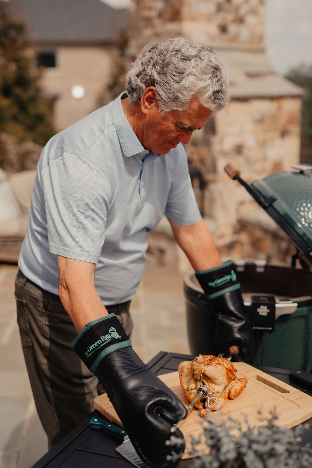Man preparing a roasted turkey outdoors next to a grill.