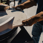 Person wearing Hell Hands gloves holding a Big Green Egg accessory outdoors
