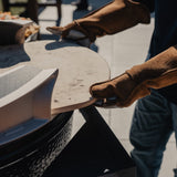 Person wearing Hell Hands gloves holding a Big Green Egg accessory outdoors