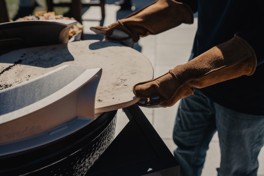 Person wearing Hell Hands gloves holding a Big Green Egg accessory outdoors