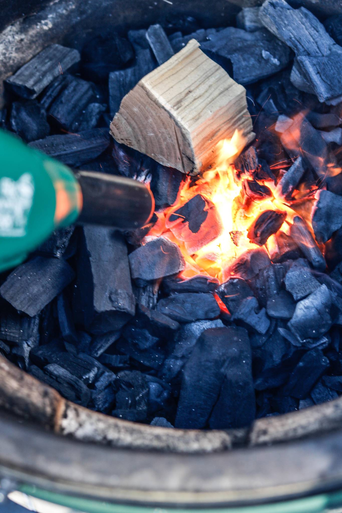 Charcoal briquettes with a lit wooden block for smoking food.