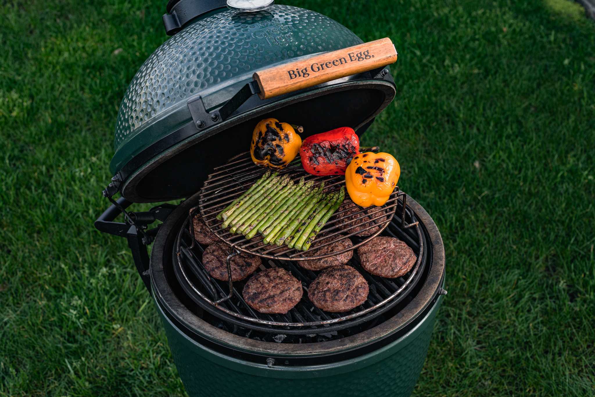 Big Green Egg grill with food on a grassy background