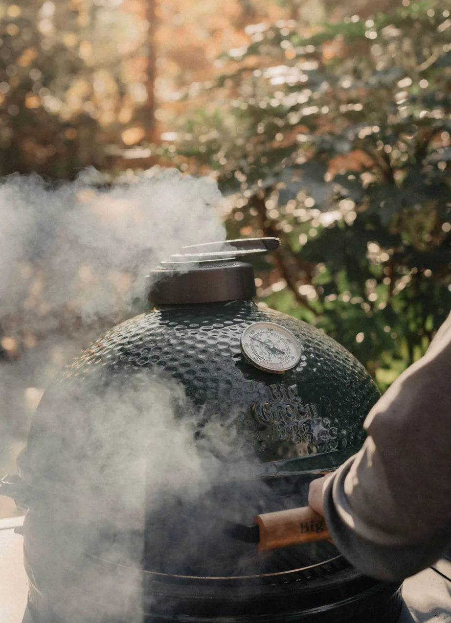 Smoking barbecue grill outdoors with trees in the background