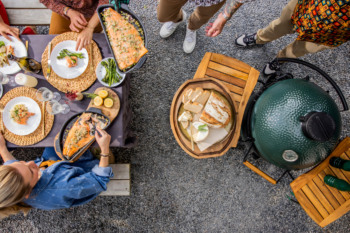 Top-down view of a group of people around a table with food and a barbecue grill.
