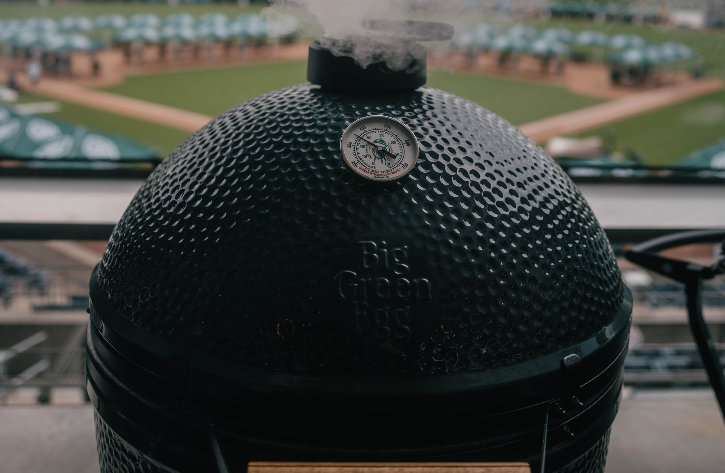 Big Green Egg barbecue grill with on a sports field background