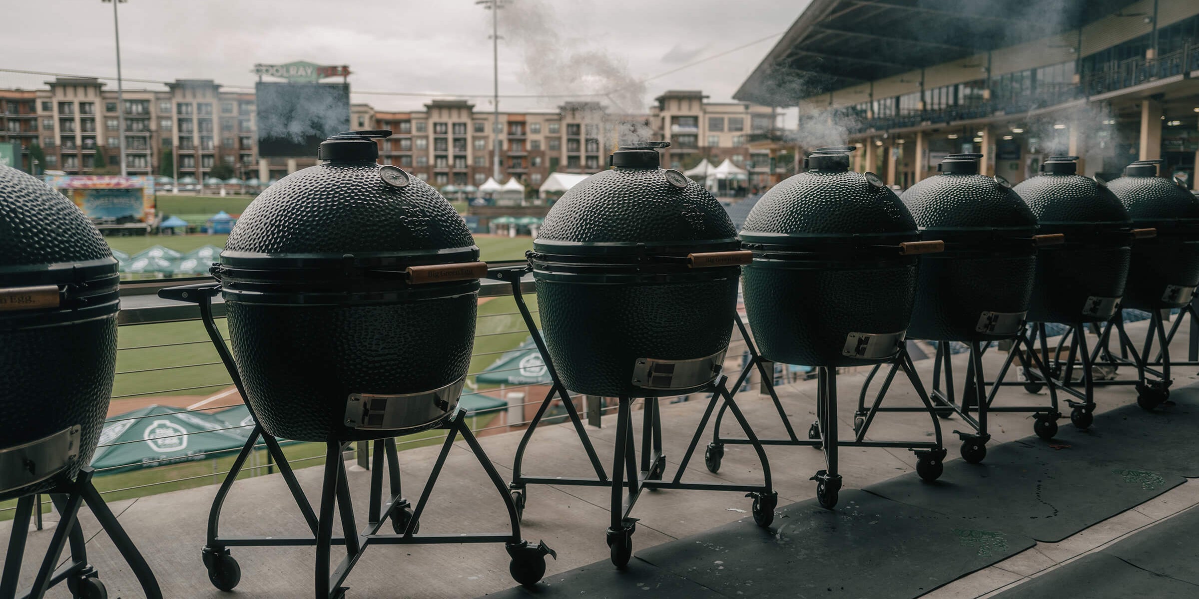Row of large barbecue grills on wheels at a sports stadium.
