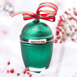 Green textured container with 'Big Green Egg' branding and a red and green ribbon on a blurred background.