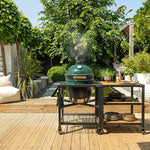 Green grill on a wooden deck with outdoor furniture and plants