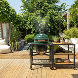 Green grill on a wooden deck with outdoor furniture and plants