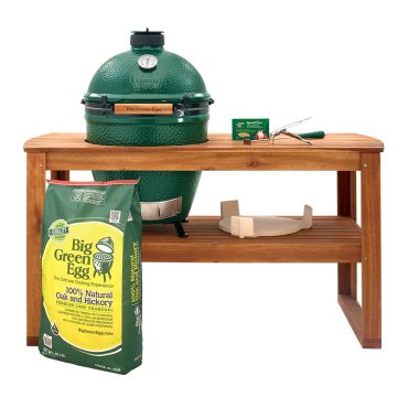 Large Big Green Egg housed in an acacia wood table and table nest, along with common tools and EGGsessories for cooking and maintenance