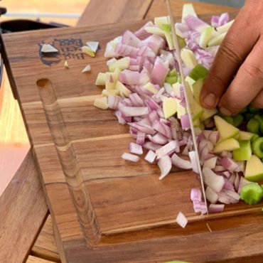 red onion, celery being chopped on Big Green Egg Cutting board